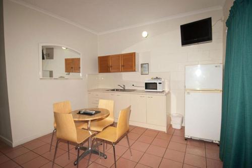 a kitchen with a table and chairs and a refrigerator at Whitsunday on The Beach in Airlie Beach