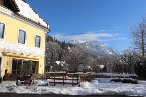 a building with a table and chairs in the snow at Pension Leano in Nötsch