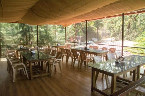 a dining room with tables and chairs and windows at Arthigamya Beach Front Resort & SPA in Gokarna