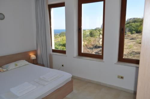 Beautiful family villa with sea view في بايالا: غرفة نوم بثلاث نوافذ وسرير بإطلالة
