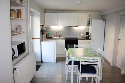 - une cuisine avec une table, des chaises et des appareils électroménagers blancs dans l'établissement Maison charmante à Gottenhouse + Jardin, à Gottenhouse