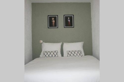 1 dormitorio con 1 cama blanca y 2 cuadros en la pared en Knus familiehuisje nabij Bergen en Schoorl, en Warmenhuizen