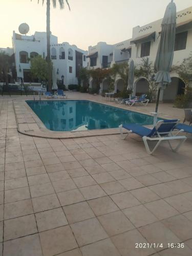 a swimming pool with a chair and a chaise at Six Corners Resort in Abū Sulţān