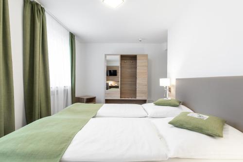 a bedroom with a large bed with white sheets and green pillows at Köln 2020 in Cologne