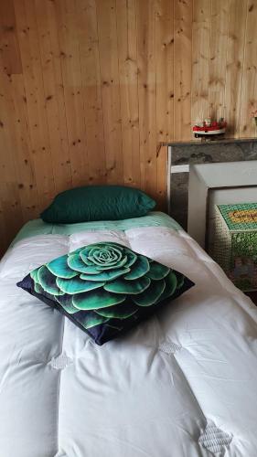 a white bed with a green pillow on it at Horizon Aubrac Laguiole in Laguiole