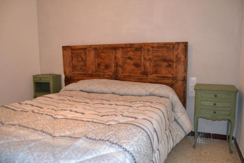 a bed with a wooden headboard and a night stand at Xalet a primera linea de mar in Calafat