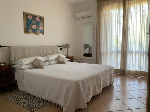 1 dormitorio con cama blanca y ventana en Appartamento con terrazza panoramica en Forte dei Marmi