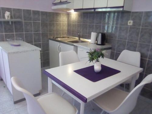 a kitchen with a white table and white chairs at Apartments Villa Ivanka in Podstrana