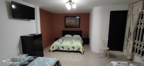 1 dormitorio con 1 cama y TV en Casa Paraíso, en Manta