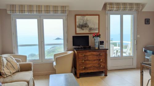 un soggiorno con due finestre e una TV di La Conchee a Saint Malo