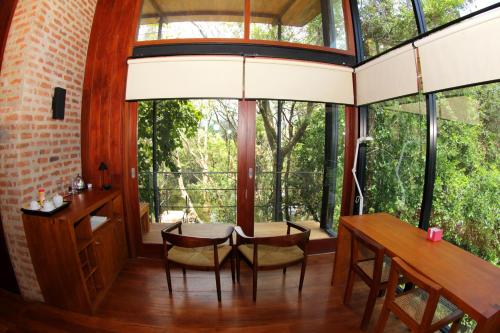 a dining room with a table and chairs and large windows at Kalundewa Retreat in Dambulla