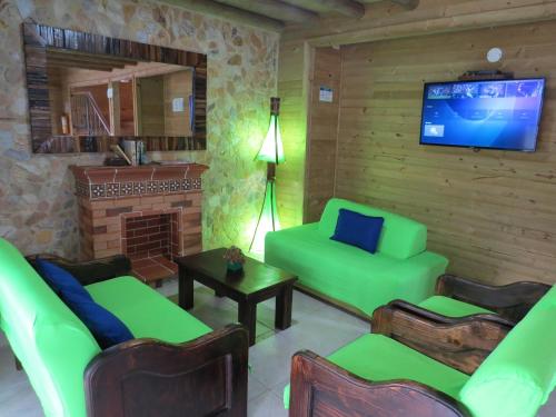 sala de estar con muebles verdes y chimenea en Cabañas Filadelfia, en Santa Rosa de Cabal