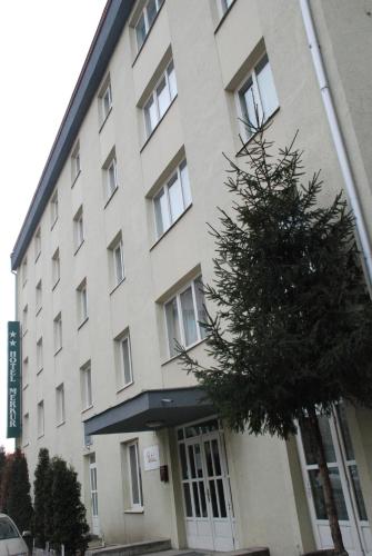 a large white building with a tree in front of it at Hotel Merkur in Miercurea-Ciuc