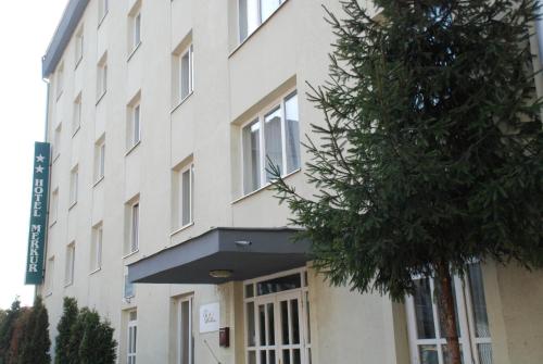 a building with a tree in front of it at Hotel Merkur in Miercurea-Ciuc