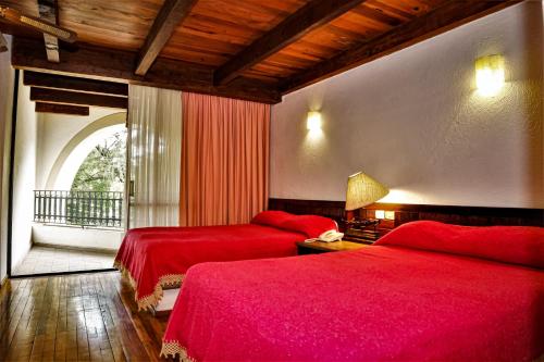 two beds in a room with red sheets at Hotel Del Parque in Tequisquiapan