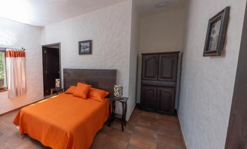Hostal Maria Tepozteca في تيبوزتلان: غرفة نوم مع سرير وبطانية برتقالية
