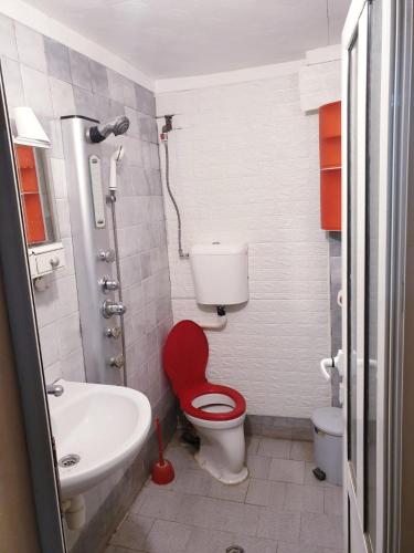 a bathroom with a red toilet and a sink at 2 стаен до парка in Razgrad