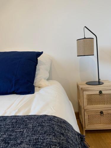a bed with a blue pillow and a lamp on a night stand at BLUE MOON in Saint-Nazaire