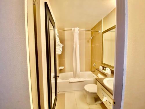 a white bathroom with a toilet and a sink at Ramada by Wyndham Whitecourt in Whitecourt