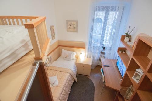 Habitación pequeña con cama y escritorio. en Casa degli Orti, Dolomia best home, en Trento
