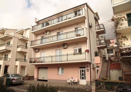 ein Gebäude mit Balkon, Tisch und Auto in der Unterkunft Apartman Mario in Makarska
