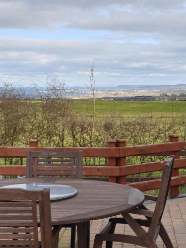 a wooden table and chairs with a view of a field at CASTLE-VIEW in Castlerock