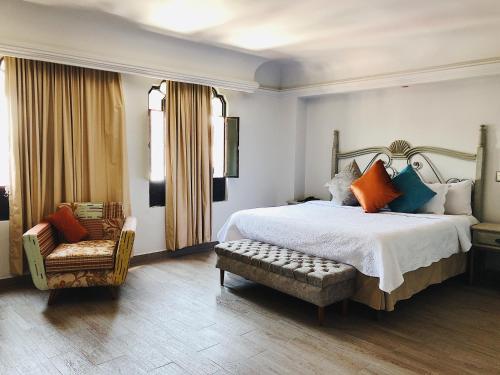 a bedroom with a large bed and a chair at Hotel Casa de los Angel's in San Juan de los Lagos