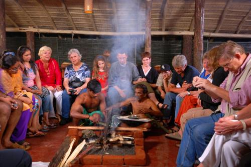 a group of people sitting around a fire pit at Carmelia Haven Resort Thekkady in Thekkady