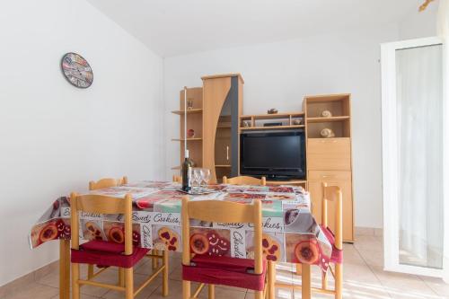 a dining room table with chairs and a television at Apartment Luka in Ivan Dolac