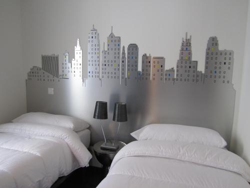 a bedroom with two beds with a city mural on the wall at Los Balcones del Arte in Santander