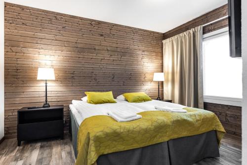 una camera da letto con un letto e una parete di legno di RukaValley Unique75 a Ruka