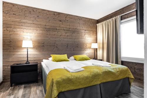 een slaapkamer met een bed en een houten muur bij RukaValley Unique75 in Ruka