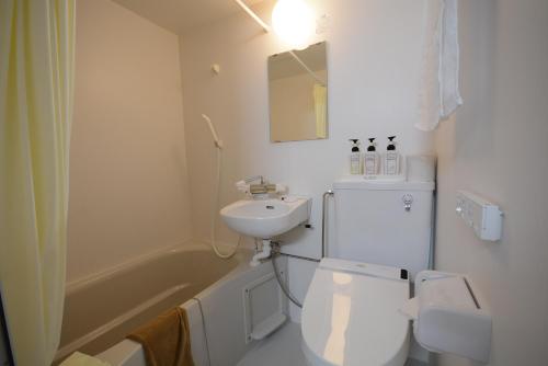 a white bathroom with a toilet and a sink at Kurobe Kanko Hotel in Omachi