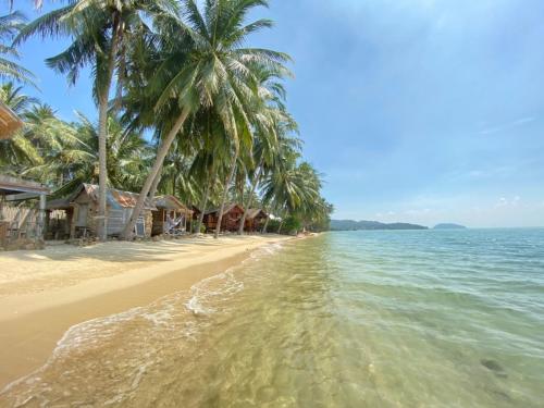 a beach with palm trees and the ocean at Castaway Beach Bungalows in Srithanu