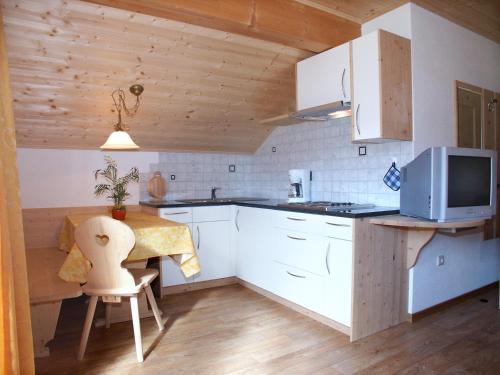 une cuisine avec des placards blancs et une table avec un four micro-ondes dans l'établissement Apartments Feldsagerhof, à Villabassa