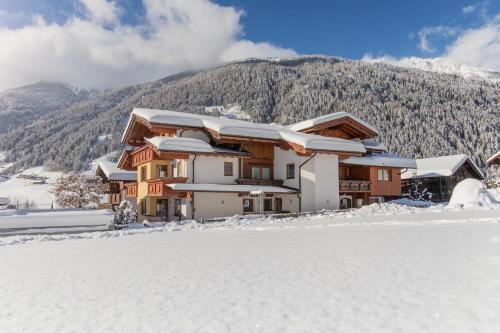 ein schneebedecktes Haus vor einem Berg in der Unterkunft Haus Rosmarie in Neustift im Stubaital