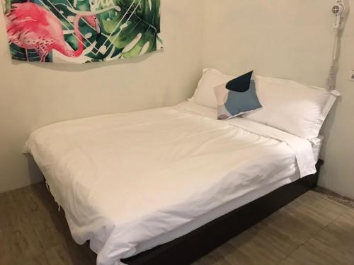 a bed with white sheets and pillows in a room at Ola Nanwan Guesthouse in Nanwan