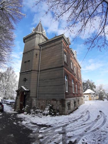 um edifício antigo com uma torre na neve em B&B Chatelet Cremers em Verviers