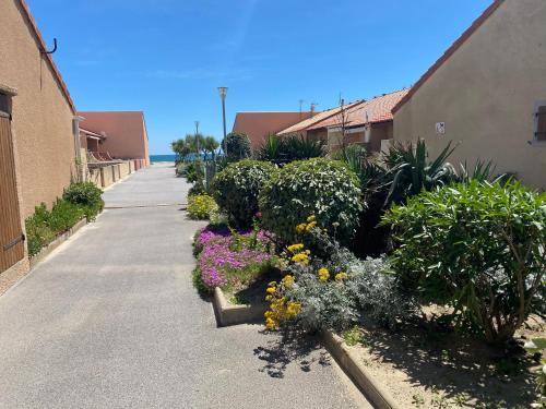 un jardin de fleurs et de plantes sur un trottoir dans l'établissement Leucate, maison dans village naturiste Eden à 50 m de la plage, 4 personnes, à Leucate