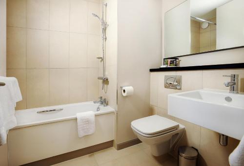 La salle de bains est pourvue d'un lavabo, de toilettes et d'une baignoire. dans l'établissement Heston Hyde Hotel, à Hounslow
