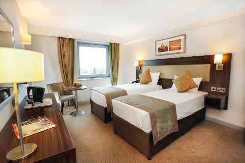 a hotel room with two beds and a desk at Heston Hyde Hotel in Hounslow