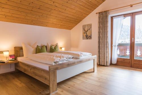 una camera con un grande letto e un soffitto in legno di Ferienwohnungen Beim Zellerbäck a Ruhpolding