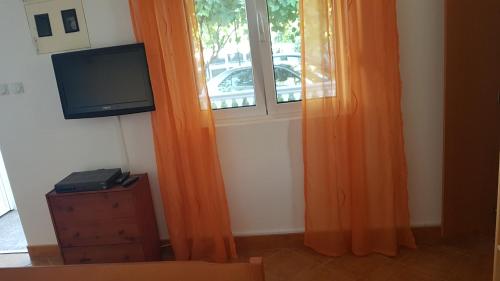 ein orangefarbener Vorhang in einem Zimmer mit Fenster in der Unterkunft Studios Velika Plaža in Ulcinj