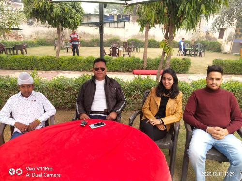 a group of people sitting around a red table at Radha Krishna Dham in Vrindāvan