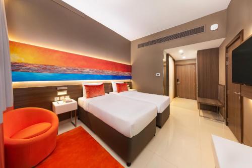 a bedroom with a large bed and a orange chair at Citymax Hotel Al Barsha in Dubai