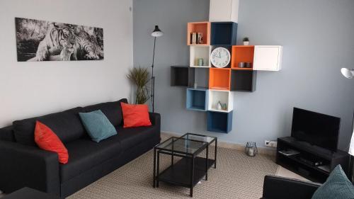 a living room with a black couch and a tv at Chambre paisible tout confort in Courcouronnes