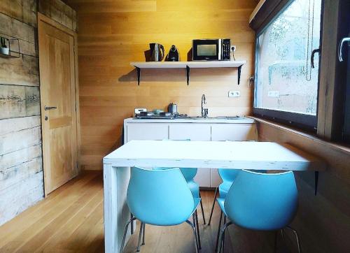 uma cozinha com uma mesa branca e cadeiras azuis em De linderd em Aalst