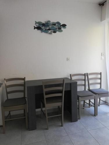 une table à manger avec quatre chaises, une table et une horloge dans l'établissement Maison près de la plage, à Port-la-Nouvelle