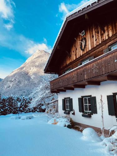 a snow covered building with a mountain in the background at Forest Chalet, 15 min to salzburg olt town, and most beautiful lakes, secluded location, 1,000 sqm garden, mountainview, panorama sauna, bath whirlpool, BBQ&bikes&sunbeds for free, up to 10 p in Golling an der Salzach