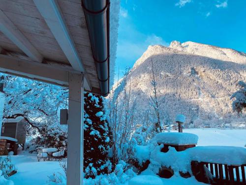 a snow covered yard with a table and a mountain at Forest Chalet, 15 min to salzburg olt town, and most beautiful lakes, secluded location, 1,000 sqm garden, mountainview, panorama sauna, bath whirlpool, BBQ&bikes&sunbeds for free, up to 10 p in Golling an der Salzach